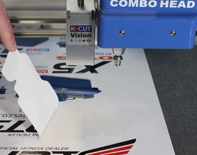 Kiss cut sticker peeling cleanly from its backing sheet, demonstrating precise kiss cutting results using a DYSS digital cutter.